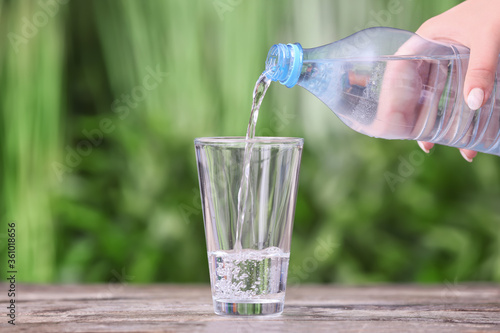 Pouring of water into glass on table outdoors