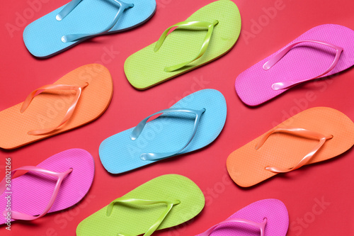 Many stylish flip-flops on color background