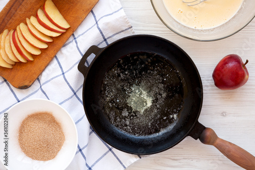 Cooking Apple Dutch Pannekoek Pancake on a white wooden surface, top view. Overhead, from above. photo