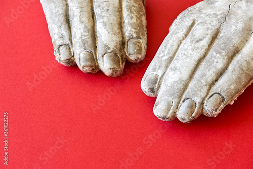 Foto Two white weathered broken hands of a stone statue on a red background
