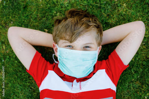 Adorable kid boy in medical mask as protection against pandemic coronavirus quarantine disease. School child using protective equipment as fight against covid 19.