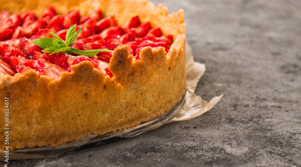 Fresh homemade strawberry shortcrust tart pie stuffed with custard vanilla cream . Sliced berries and mint leaf on the trendy dark grey concrete background. Free copy space. Top view. Fresh homemade strawberry shortcrust tart pie stuffed with custard vanilla cream . Sliced berries and mint leaf on the trendy dark grey concrete background. Free copy space. Top view.