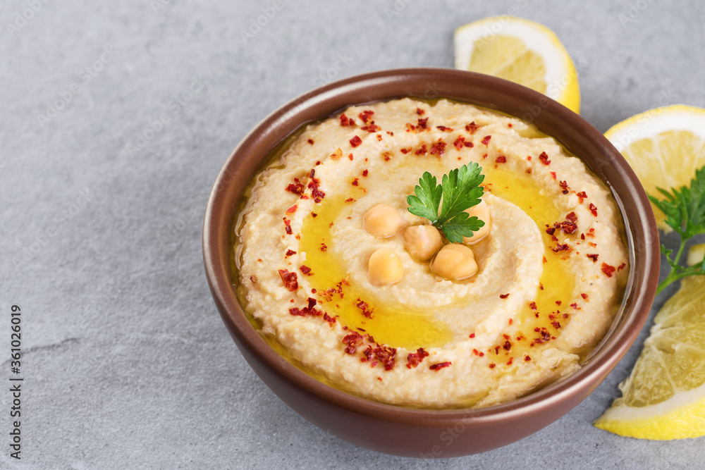 Chickpeas hummus with olive oil, paprika, parsley and lemon on a gray background. Chickpeas hummus with olive oil, paprika, parsley and lemon on a gray background.