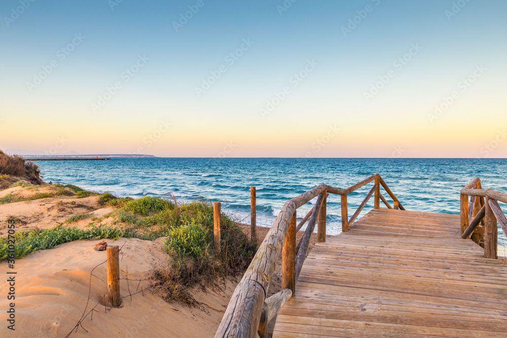 wooden access over the dunes to the beach with a view of the horizon over the sea at sunset. Guardamar, Alicante. Spain