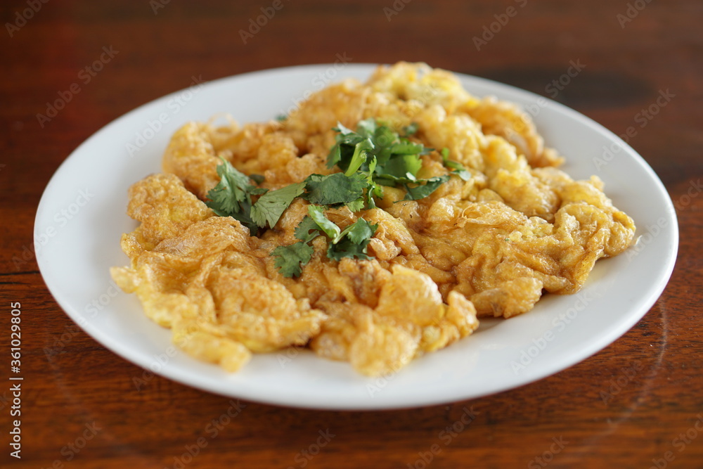Side view of Omelet and top with coriander on wood table.(Thai style) Side view of Omelet and top with coriander on wood table.(Thai style)