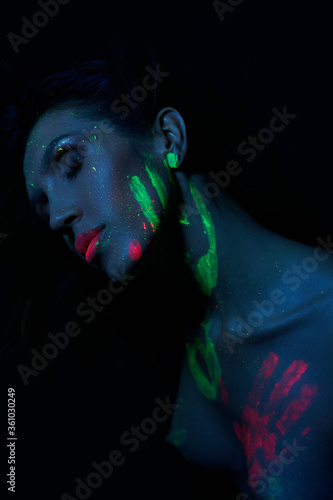 Sexy Nude woman in neon light, UV paint on the woman face and body. Perfect figure and Breasts of a woman, beautiful hair