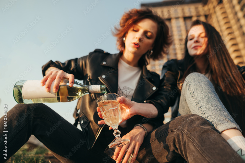 Φωτογραφία Closeup photo of a girl pours wine from a bottle into a glass on the street