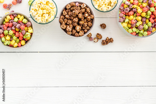 Colorful popcorn in bowl on white desk top-view copy space