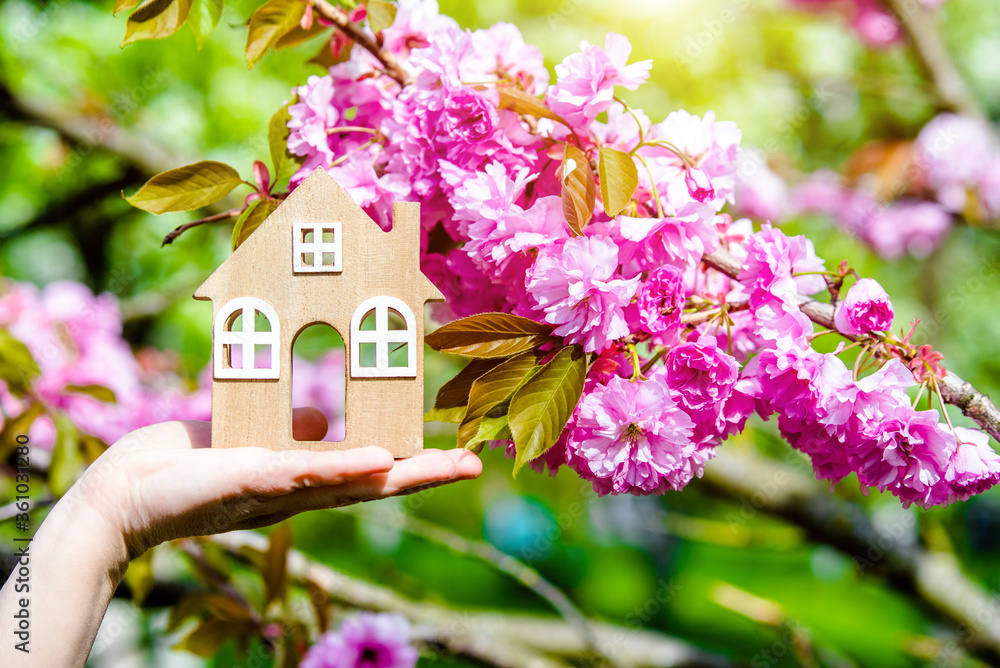 The girl holds the house symbol against the background of blossoming Sakura The girl holds the house symbol against the background of blossoming Sakura