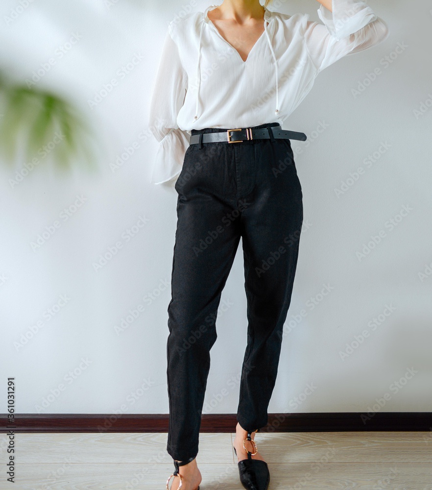 Woman posing in shirt and black pants. Beautiful young Woman posing in a white  blouse, black pants with a black belt. Black jeans close-up. Stock Photo |  Adobe Stock