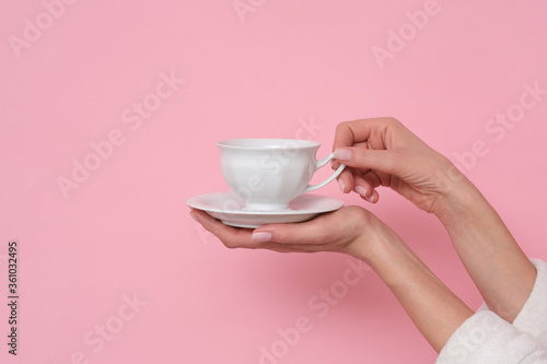 Coffe mood. Woman in white bath robe is holding a cup of coffee. Studio shoot on pink background.