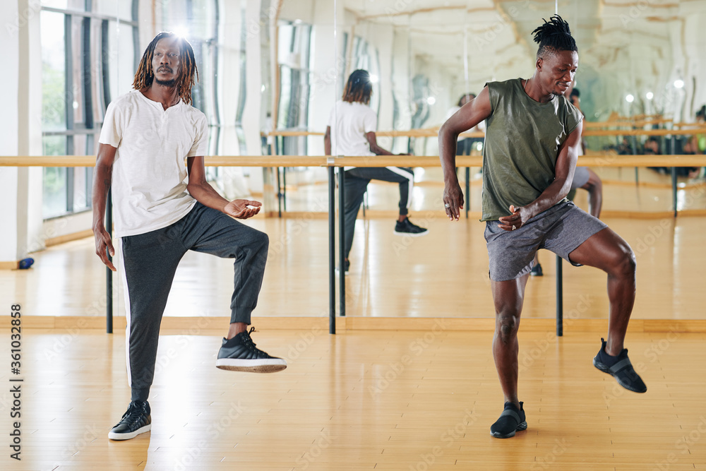 Young Black man attending dance class and repeating movement after the teacher