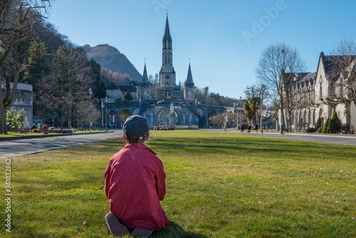 young boy with the cathedral-sanctuary of Lourdes (France)