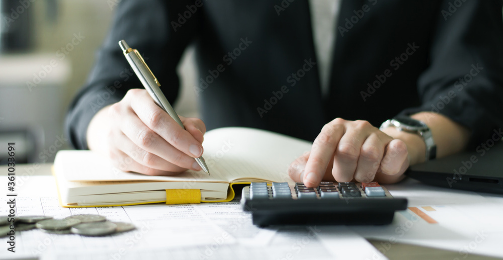 accountant working at a table using a calculator to calculate numbers, financial accounting concept. Finance accountant working at a table using a calculator to calculate numbers, financial accounting concept. Finance