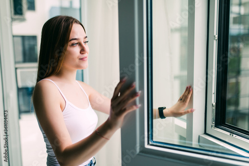 Young pretty woman opening window in living room