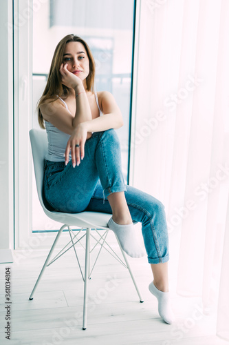 Young woman resting in chair at home near window