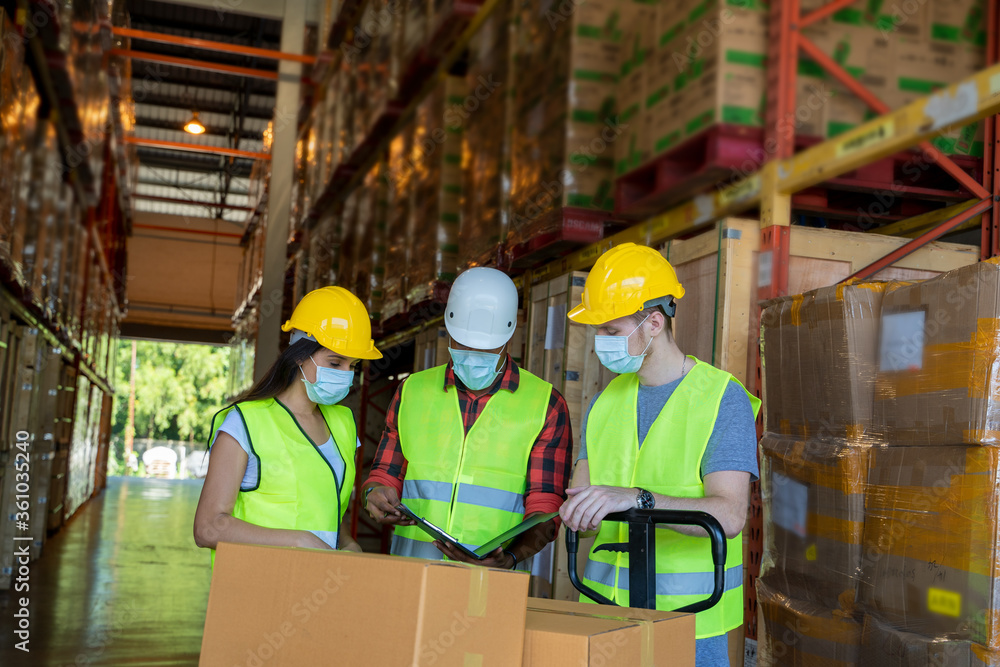 Warehouse workers wearing protective mask to Protect Against Covid-19 with clipboard during work in a warehouse. Warehouse workers wearing protective mask to Protect Against Covid-19 with clipboard during work in a warehouse.