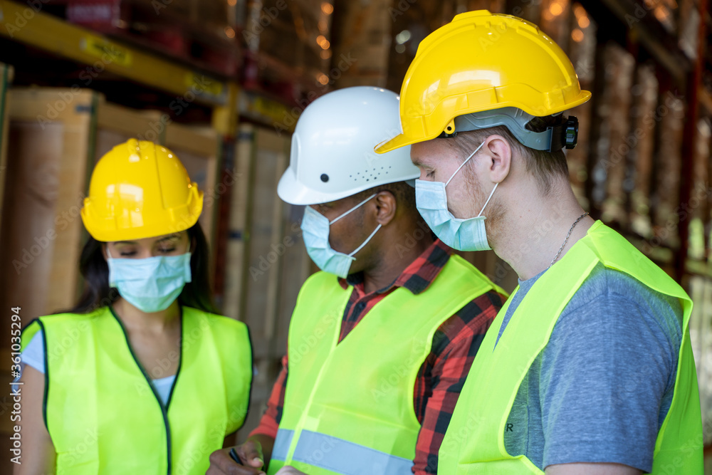 Warehouse workers wearing protective mask to Protect Against Covid-19 with clipboard during work in a warehouse. Warehouse workers wearing protective mask to Protect Against Covid-19 with clipboard during work in a warehouse.
