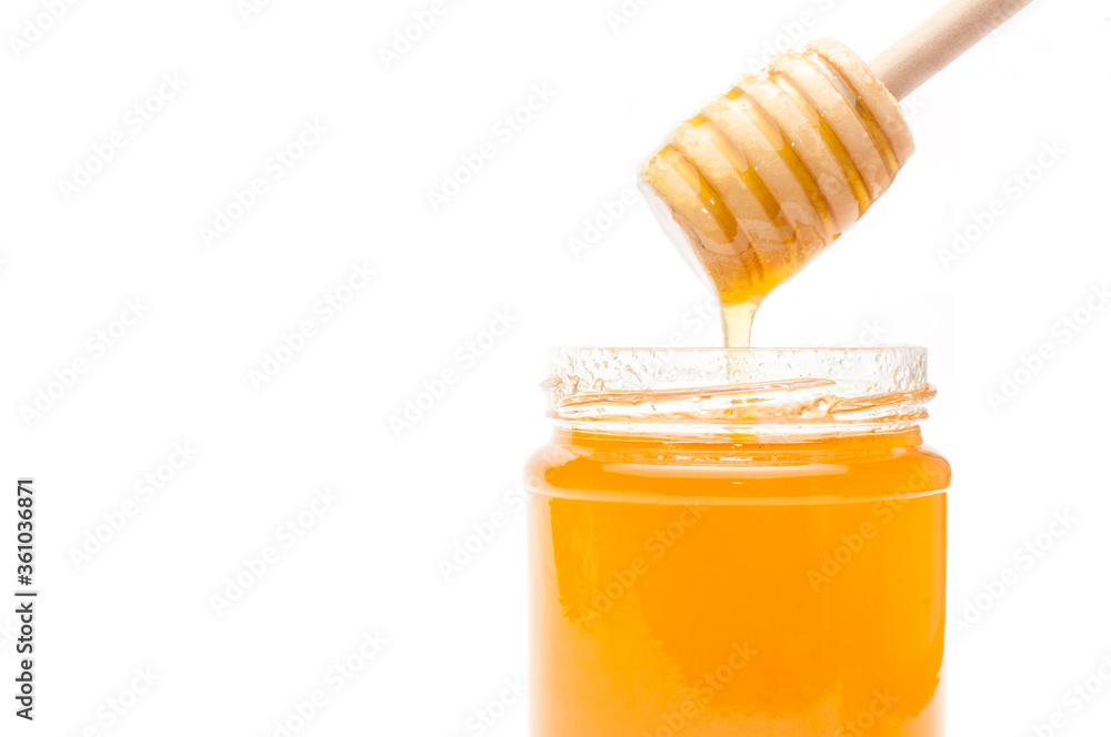 Honey dipper into a jar full of honey on white background Honey dipper into a jar full of honey on white background