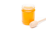Jar full of honey and honey dipper on a white background