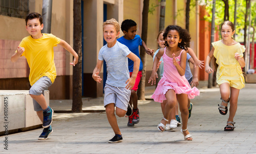 Cheerful active children are racing along the street