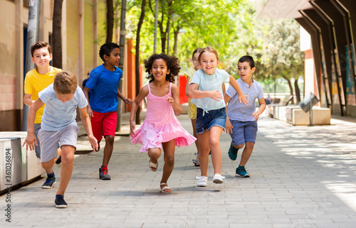 Cheerful active children are racing along the street