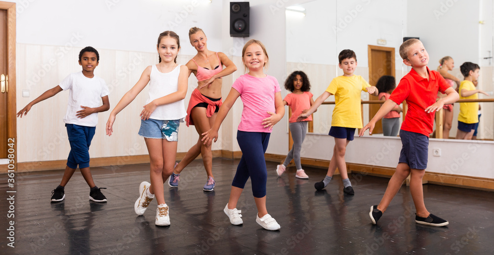 Preteen boys and girls dancing with trainer in dance hall