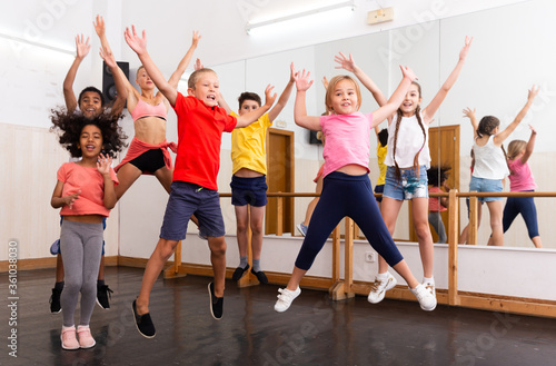 Cheerful tweens jumping with trainer during dance class