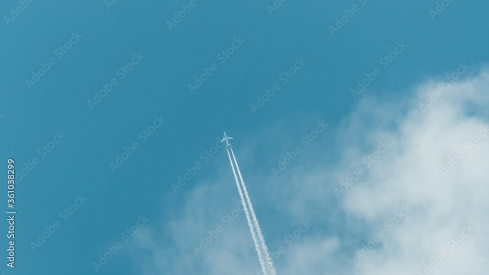 The plane takes off from the cloud. Clear transparent beautiful blue sky. White fluffy cloud. The plane flying leaves a trace of the work of its engines. Jet trail in the sky. The plane takes off from the cloud. Clear transparent beautiful blue sky. White fluffy cloud. The plane flying leaves a trace of the work of its engines. Jet trail in the sky.