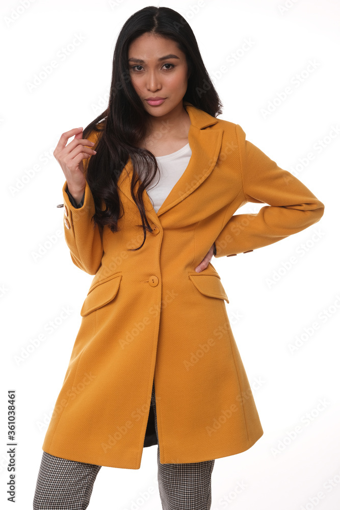 Pretty asian model in orange coat on studio shoot. Pretty asian model in orange coat on studio shoot.