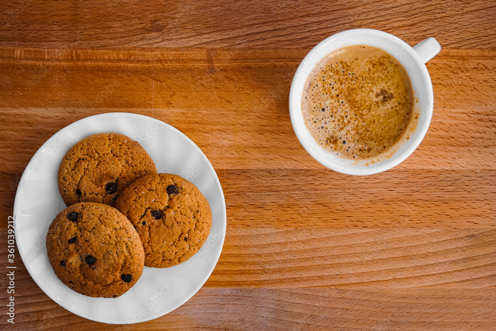 Oatmeal cookies on a plate on a table with a wooden texture and coffee Oatmeal cookies on a plate on a table with a wooden texture and coffee