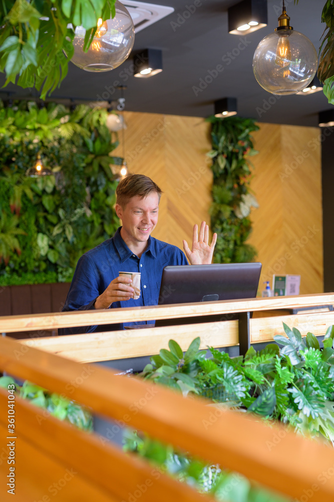 Happy young handsome businessman video calling with laptop at the coffee shop Happy young handsome businessman video calling with laptop at the coffee shop