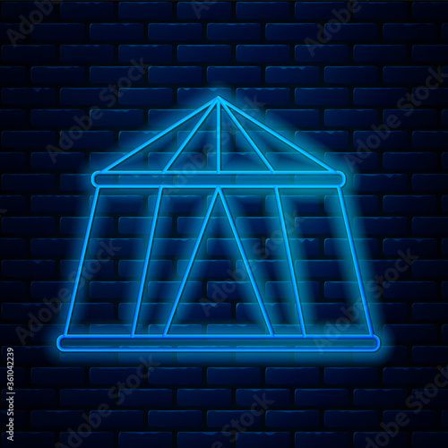 Glowing neon line Circus tent icon isolated on brick wall background. Carnival camping tent. Amusement park. Vector Illustration.