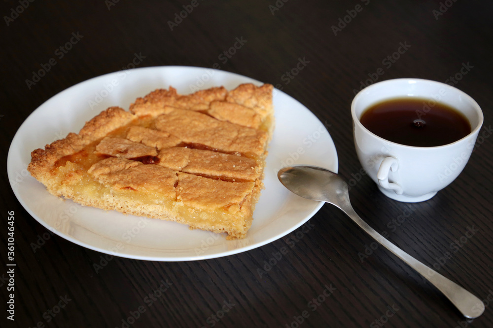 Lemon pie on white plate, cup of coffee and spoon on a wooden table. Concept of morning breakfast, sweet dessert and calories food Lemon pie on white plate, cup of coffee and spoon on a wooden table. Concept of morning breakfast, sweet dessert and calories food