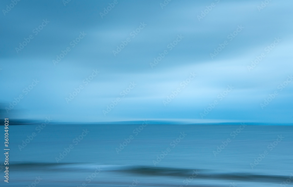 Abstract image of blue sea waves and clouds. Image captured using intentional camera movement technique for dreamy effect.