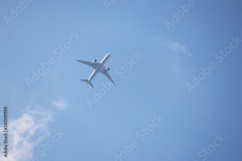 White airplane flying in the blue sky with clouds, bottom view. Two-engine commercial plane during taking off