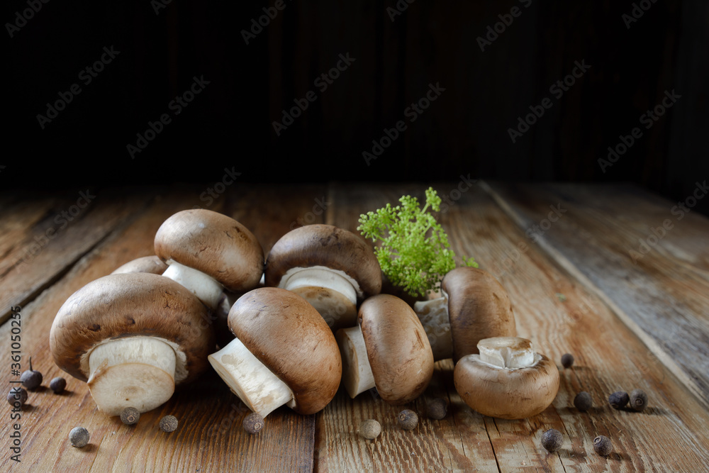 Royal mushrooms champignon whole and cut into pieces, scattered peppers, close-up on a wooden background, rustic style Royal mushrooms champignon whole and cut into pieces, scattered peppers, close-up on a wooden background, rustic style