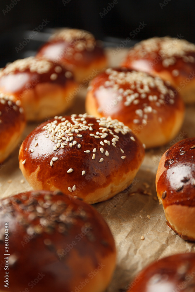 Fresh hot sweet buns with sesame seeds from the oven, homemade bakery.