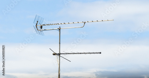 Television antenna on blue sky background with clouds. Space for copy and text