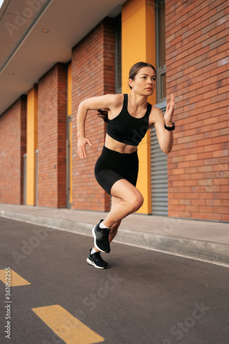 Young woman sprinting in the morning outdoors. Top view of female runner working out in the city.