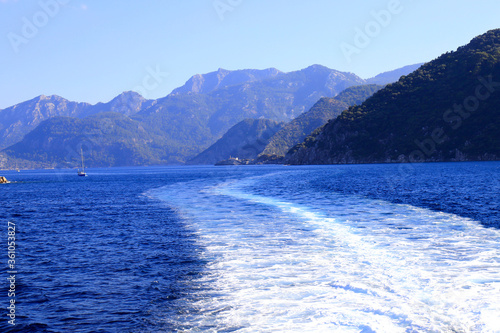 Picturesque sea view in Turkey, near Bodrum and Marmaris, a trace from a boat on the water, waves. Mountains and hills around the bay, summer resort landscape