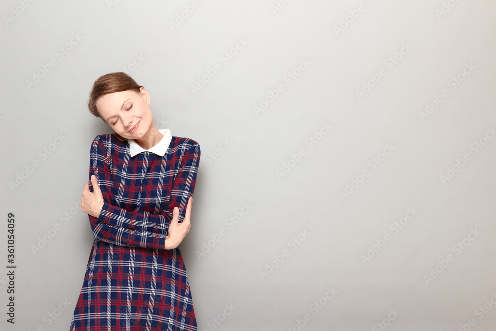 Portrait of happy girl hugging herself and smiling with closed eyes Portrait of happy girl hugging herself and smiling with closed eyes