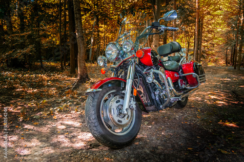 Red Road Bike Cruiser. Motorcycle cruiser stands on dirt road in sunny autumn forest. Walk ride on chopper in forest road