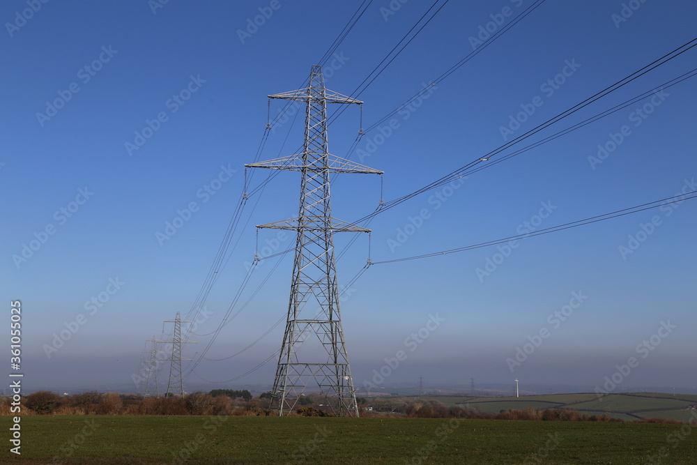 High-voltage electricity pylons overlooking farmland on a hilltop in Devon.