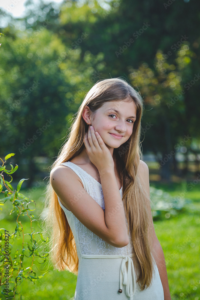 Teenager girl with long hair in white dress in summer park at sunny day Teenager girl with long hair in white dress in summer park at sunny day