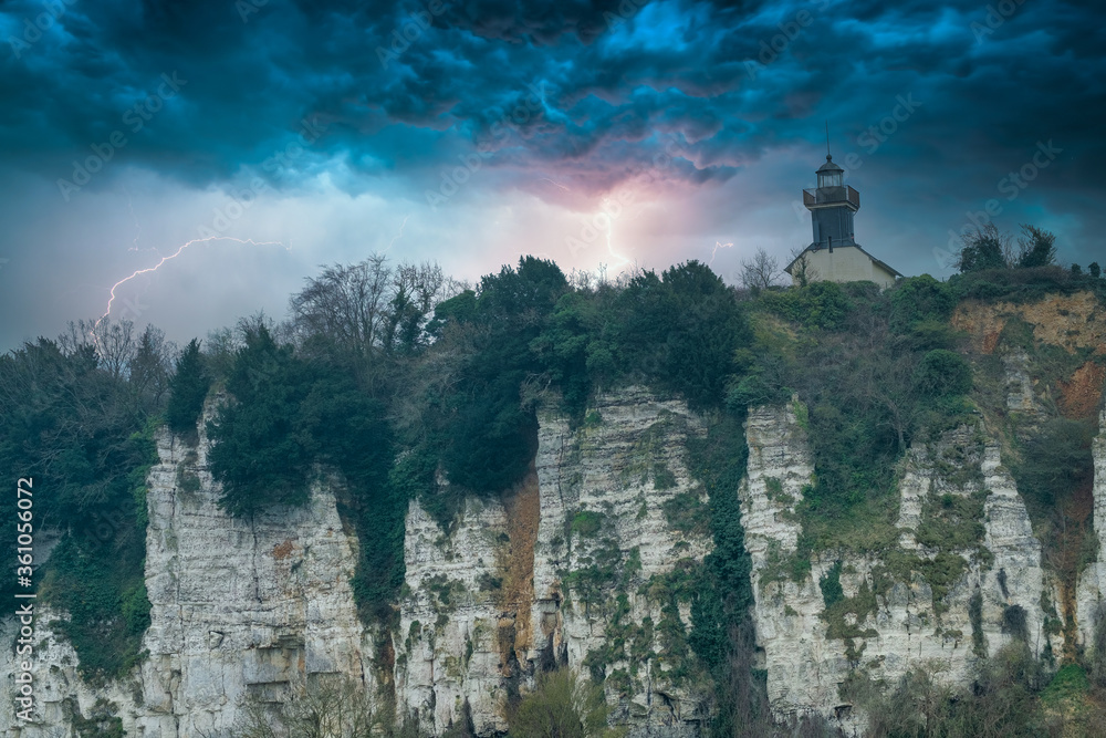 Lighthouse on a chalk cliff under a dramatic thunderstorm sky in Normandy, France