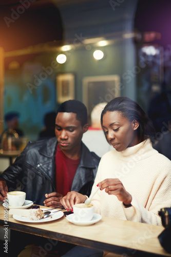 Two young friends having joint lunch in restaurant during work break  students relaxing in cafe after lectures in University  beautiful black couple get warm in coffee shop after strolling in cold day