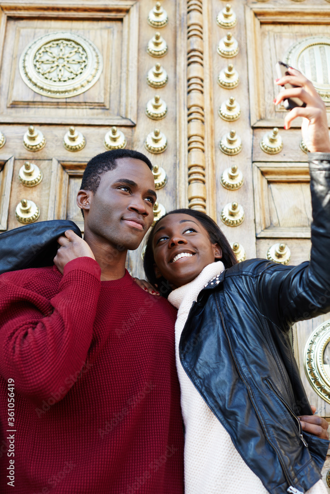 Dating couple happy in love taking self-portrait photo on beautiful antique door background, happy friends taking self portrait outdoors, tourist man and woman making self portrait with mobile phone