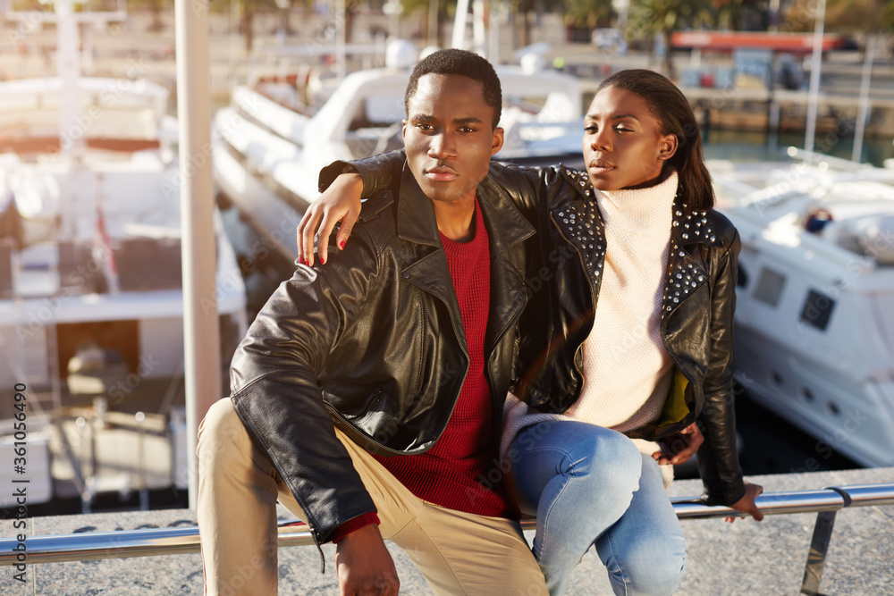 Portrait of fashionable professional couple of models posing outdoors, embracing black couple enjoying time spending together while sitting in yacht port of Barcelona, vacation holidays Portrait of fashionable professional couple of models posing outdoors, embracing black couple enjoying time spending together while sitting in yacht port of Barcelona, vacation holidays