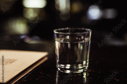 A glass of water in a dark and moody bar atmosphere, selective focus
